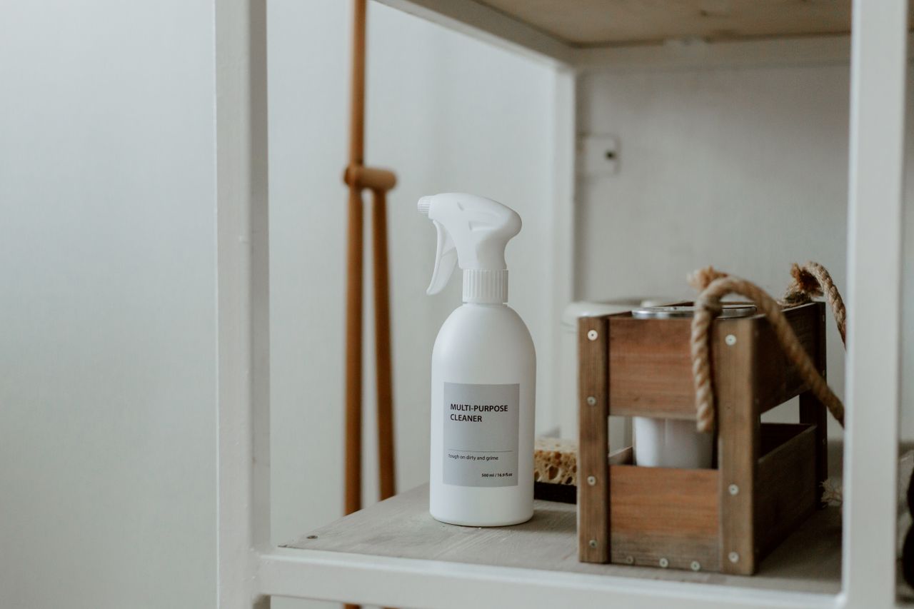 Clean white shelf with a spray cleaner and wooden caddy, ideal for organizing a home space.